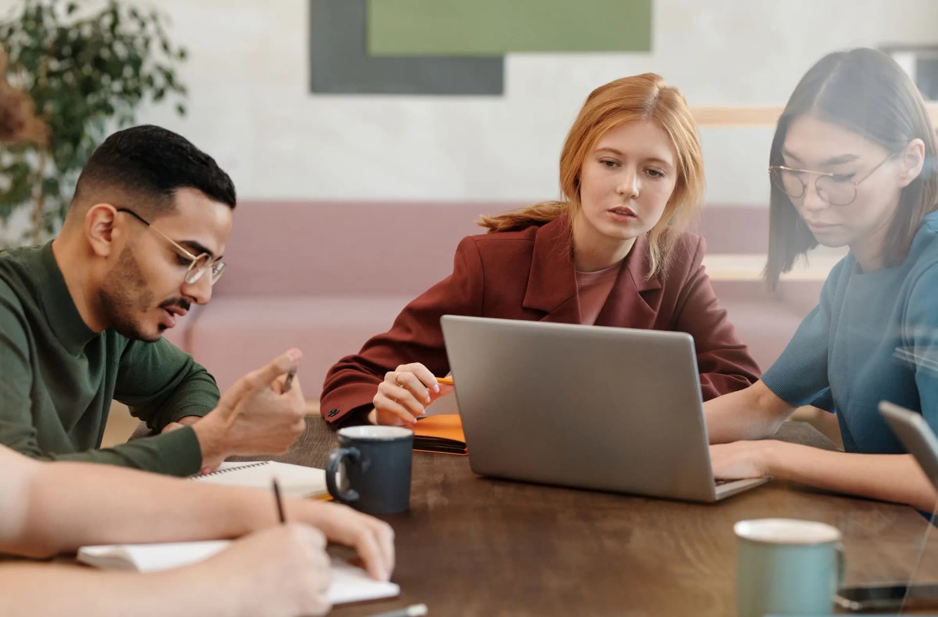 Colleagues in a meeting around a table with a laptop