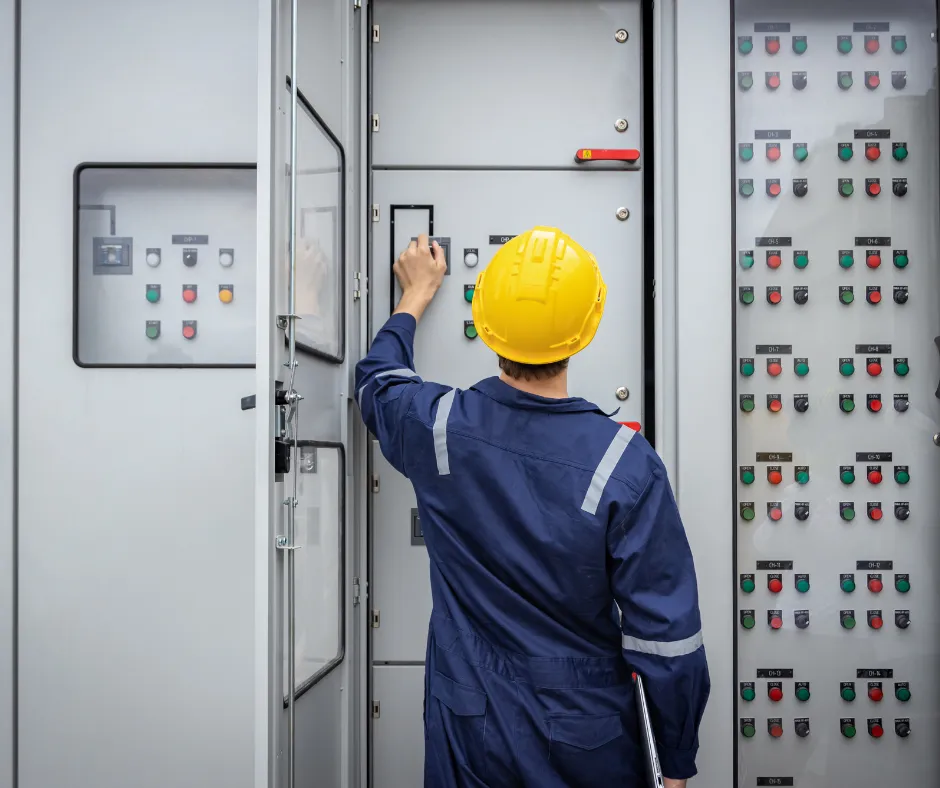 Technician in a yellow helmet working on an electrical panel