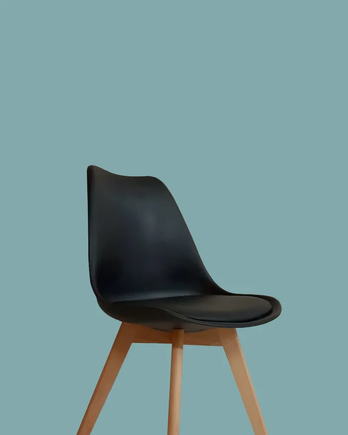 Black chair against a teal wall