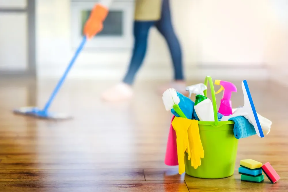 Cleaning supplies and person mopping floor