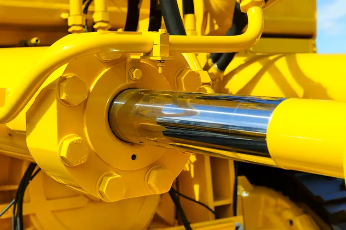 Close-up of a yellow industrial machine's hydraulic cylinder.
