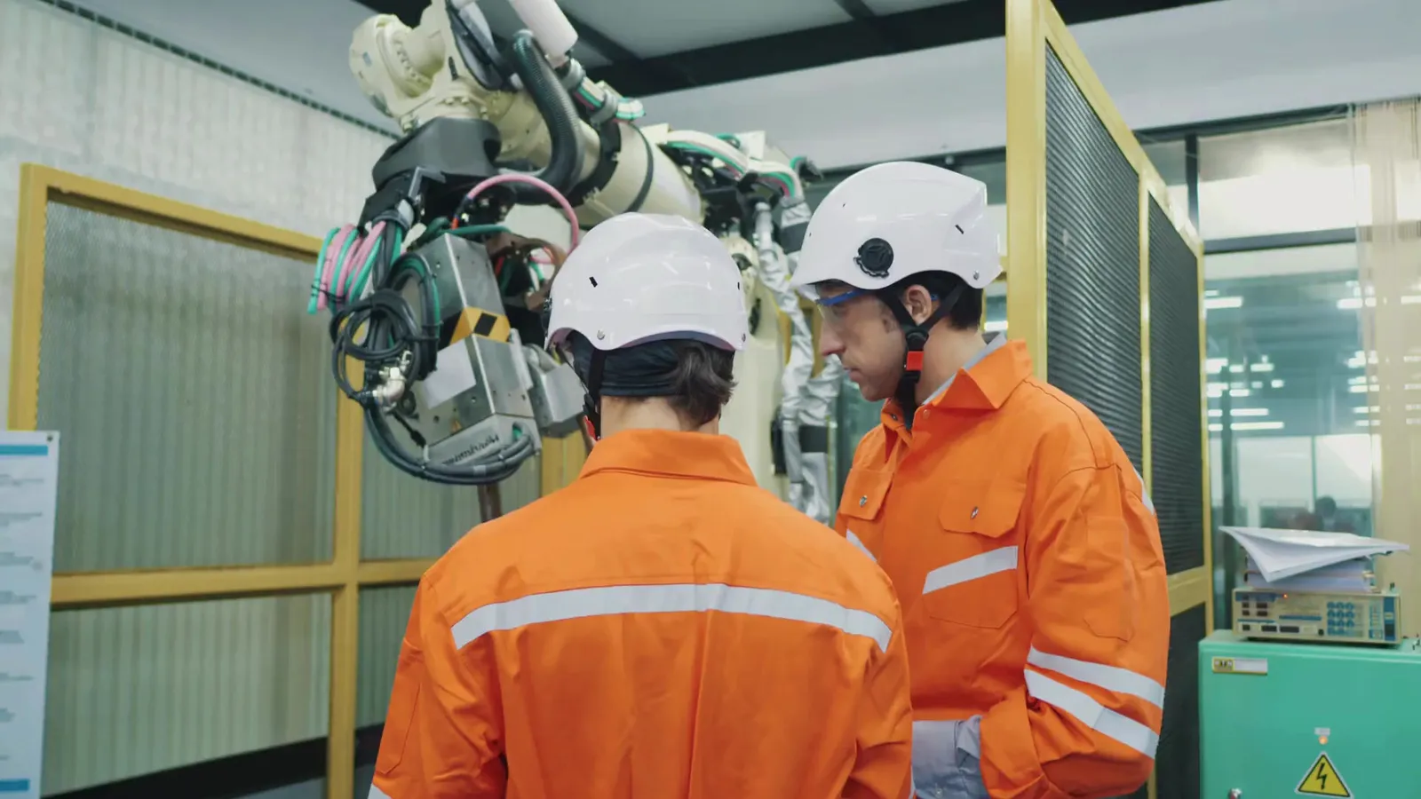 Engineers in orange workwear at an industrial machine