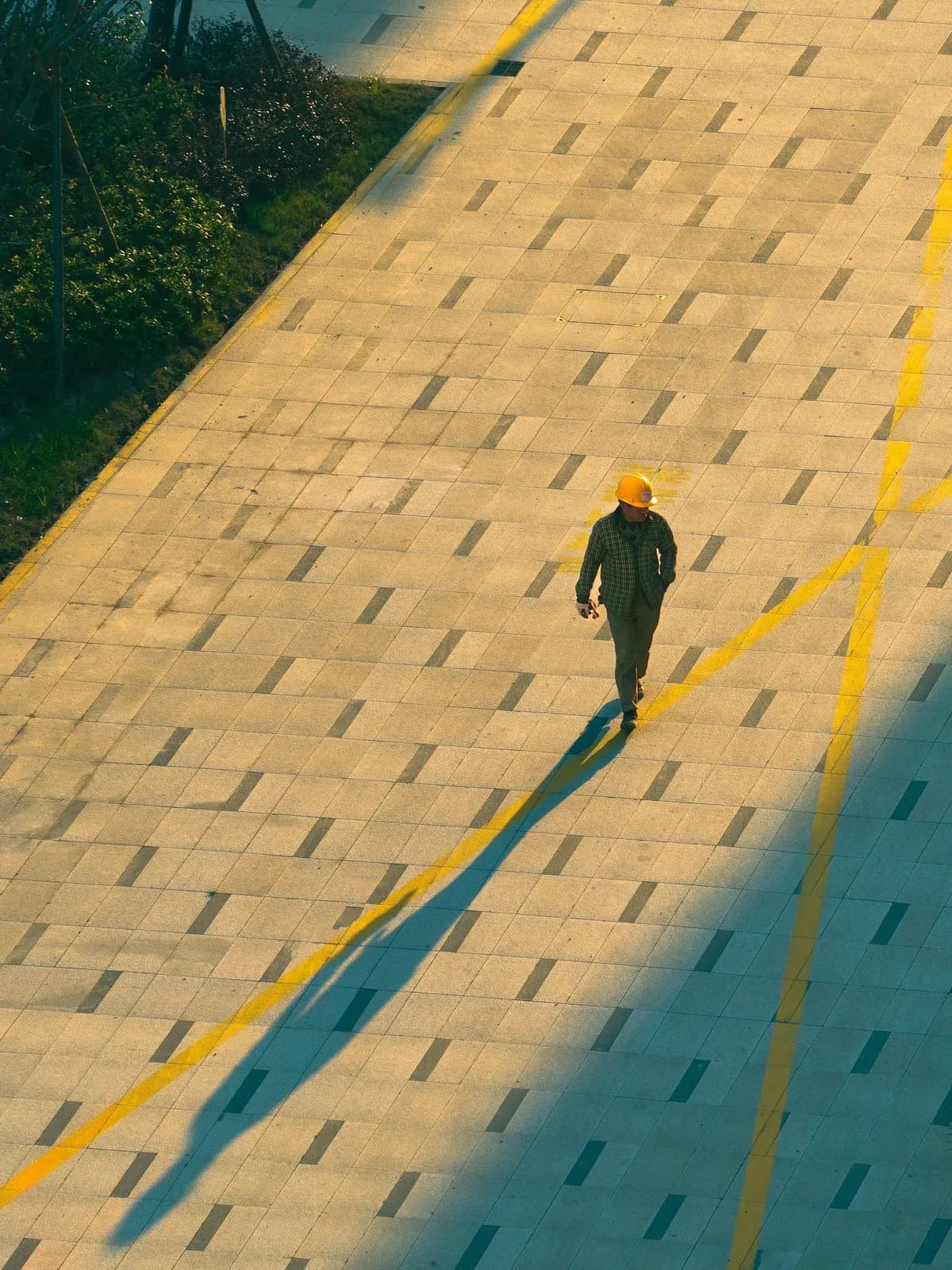 Worker in a hard hat walking across a sunlit site